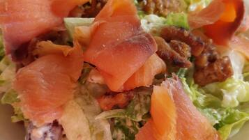 Un plato de comida con varios ingredientes, incluyendo lechuga, tocino y posiblemente carne o marisco.