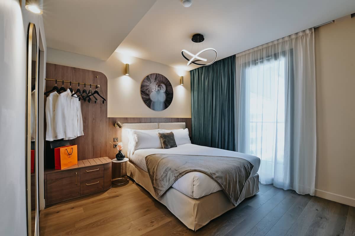A bedroom with a bed, bedside table, and a wardrobe with hanging clothes.