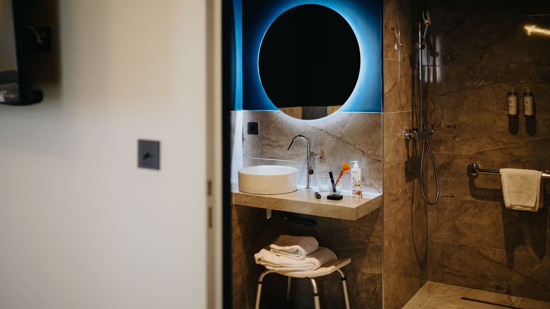 Ein modernes Badezimmer mit einem runden Spiegel, einem Waschbecken und einer Dusche.
