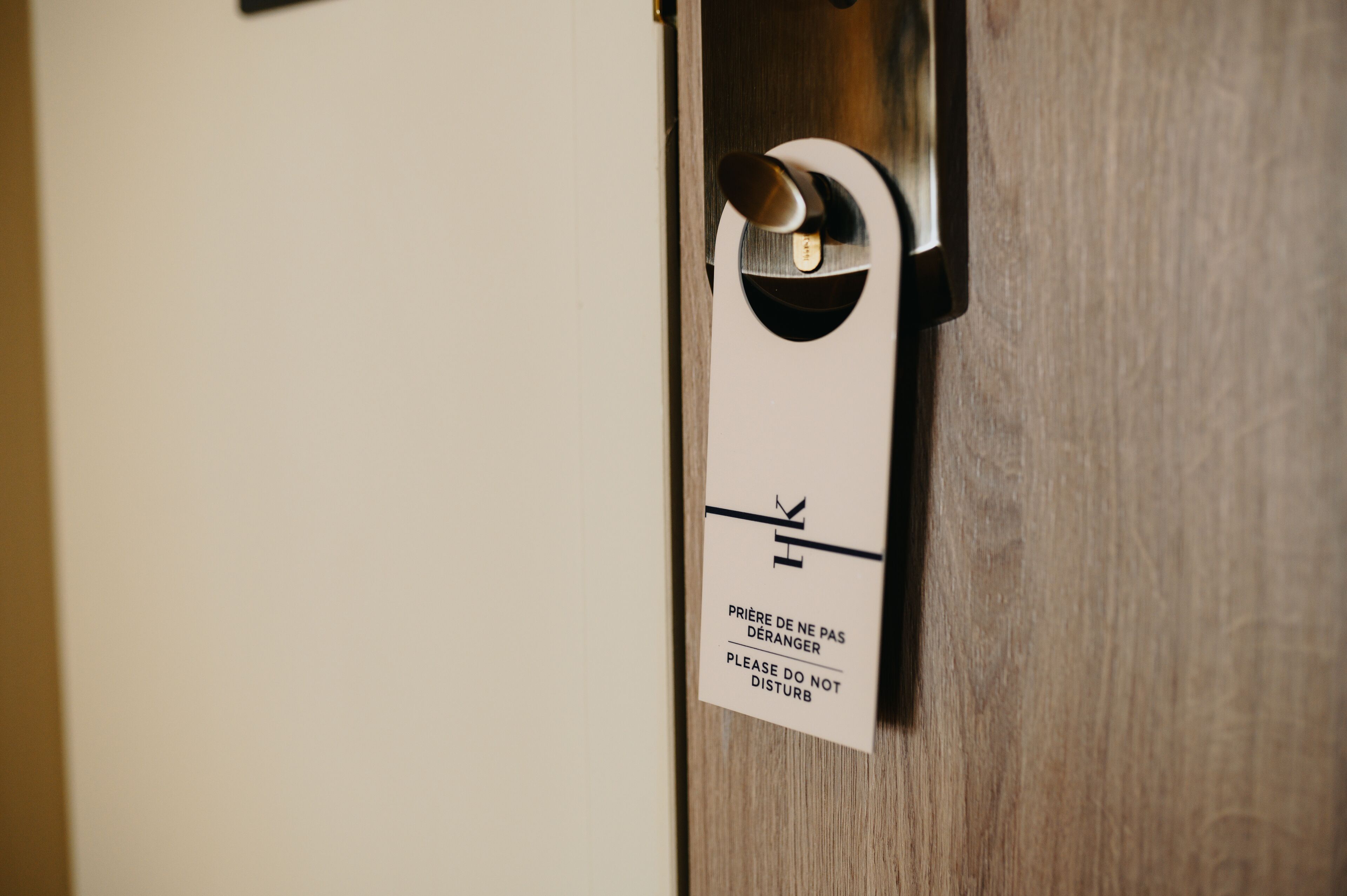 Uma porta com uma placa que diz 'PRIÈRE DE NE PAS DÉRANGER PLEASE DO NOT DISTURB' em francês.