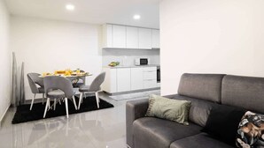 A modern living room with a grey sofa, a dining table with chairs, and a kitchen area in the background. - Upscale Trendy Flats by HostWise (Porto)