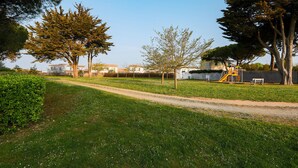 Un parc avec un sentier de terre, des arbres et une aire de jeux.