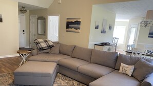 A spacious living room with a large L-shaped sectional sofa, a matching ottoman, and a patterned rug. - Bright centrally located 3 bed/2 bath with fenced private yard (Aiken)