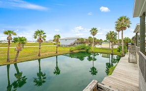 Zona residencial con piscina, muelle de madera y palmeras.
