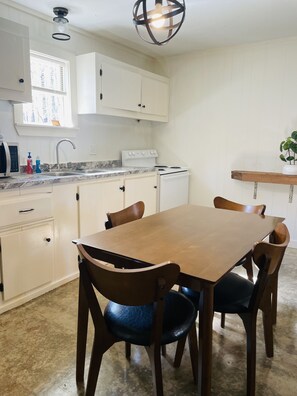 A kitchen with white cabinets, a wooden dining table, and chairs.