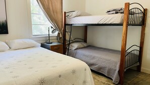 Ein Schlafraum mit Etagenbett, Einzelbett und Schreibtisch.