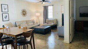 Ein Wohnzimmer mit Esstisch, zwei Sofas, einer Stehlampe und einem Deckenventilator.