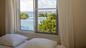 Een slaapkamer met een groot raam met uitzicht op een jachthaven en gebouwen.