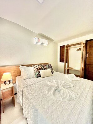 Una cama bien hecha con un cojín decorativo, una lámpara de noche y un cabecero de madera.