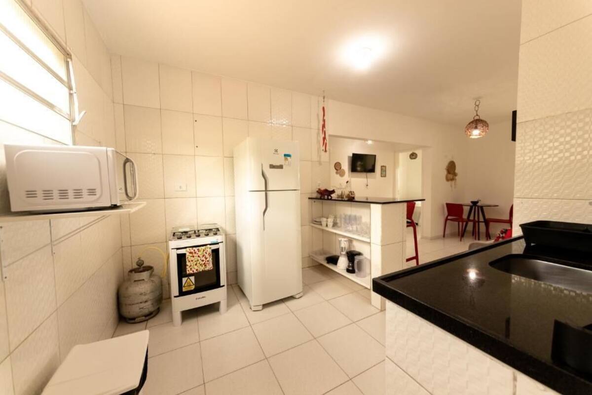 Een kleine keuken met witte apparaten, een gasfles en een kleine oven.