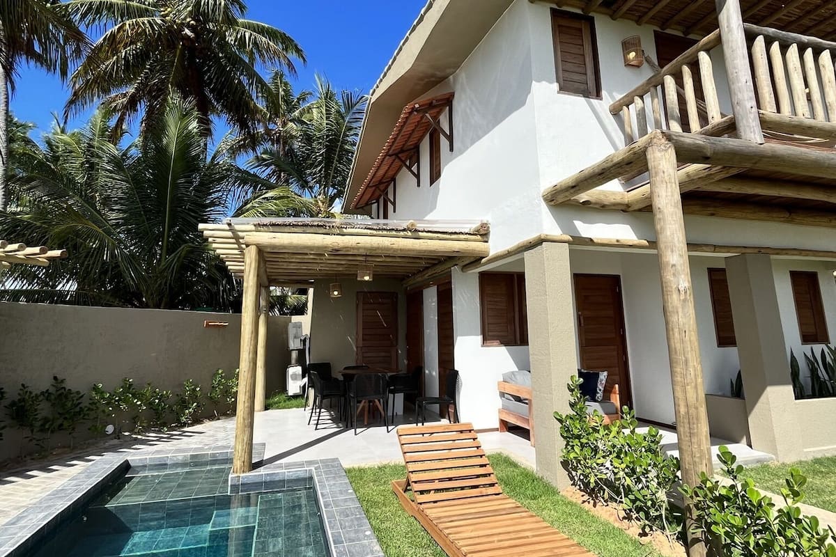 Een huis met een zwembad, een houten terras en een overdekte patio.