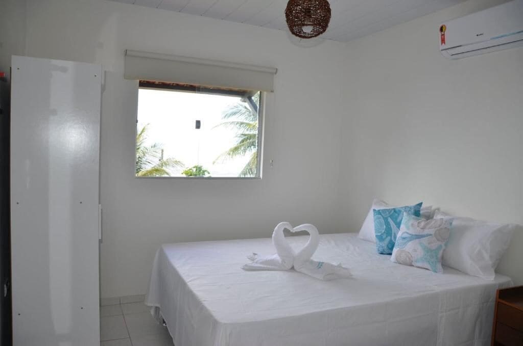 A hotel room with a bed, a window, and a wall-mounted air conditioner.
