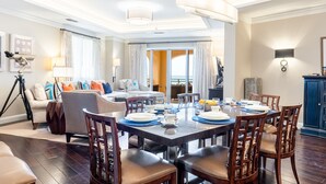 Uma sala de jantar com mesa redonda para seis pessoas, rodeada por cadeiras de madeira com assentos acolchoados.