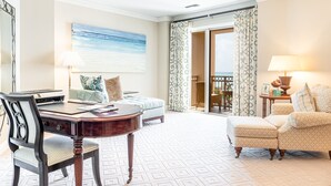 Quarto de hotel com uma mesa de jantar, um sofá, uma cadeira, um abajur e um quadro na parede.