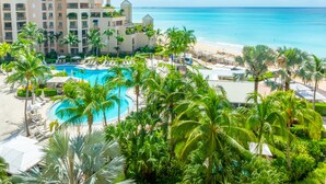 Resort com uma grande piscina rodeada por palmeiras e uma praia.