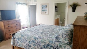 Une chambre à coucher avec un lit, une commode en bois et un téléviseur posé sur un meuble.