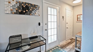 Un pasillo con una mesa de vidrio, una obra de arte en la pared y una puerta decorada con estrellas.