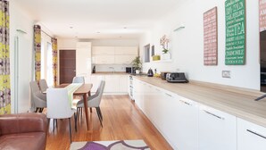 Una cocina moderna con armarios blancos, encimera de madera y un comedor con mesa y sillas.