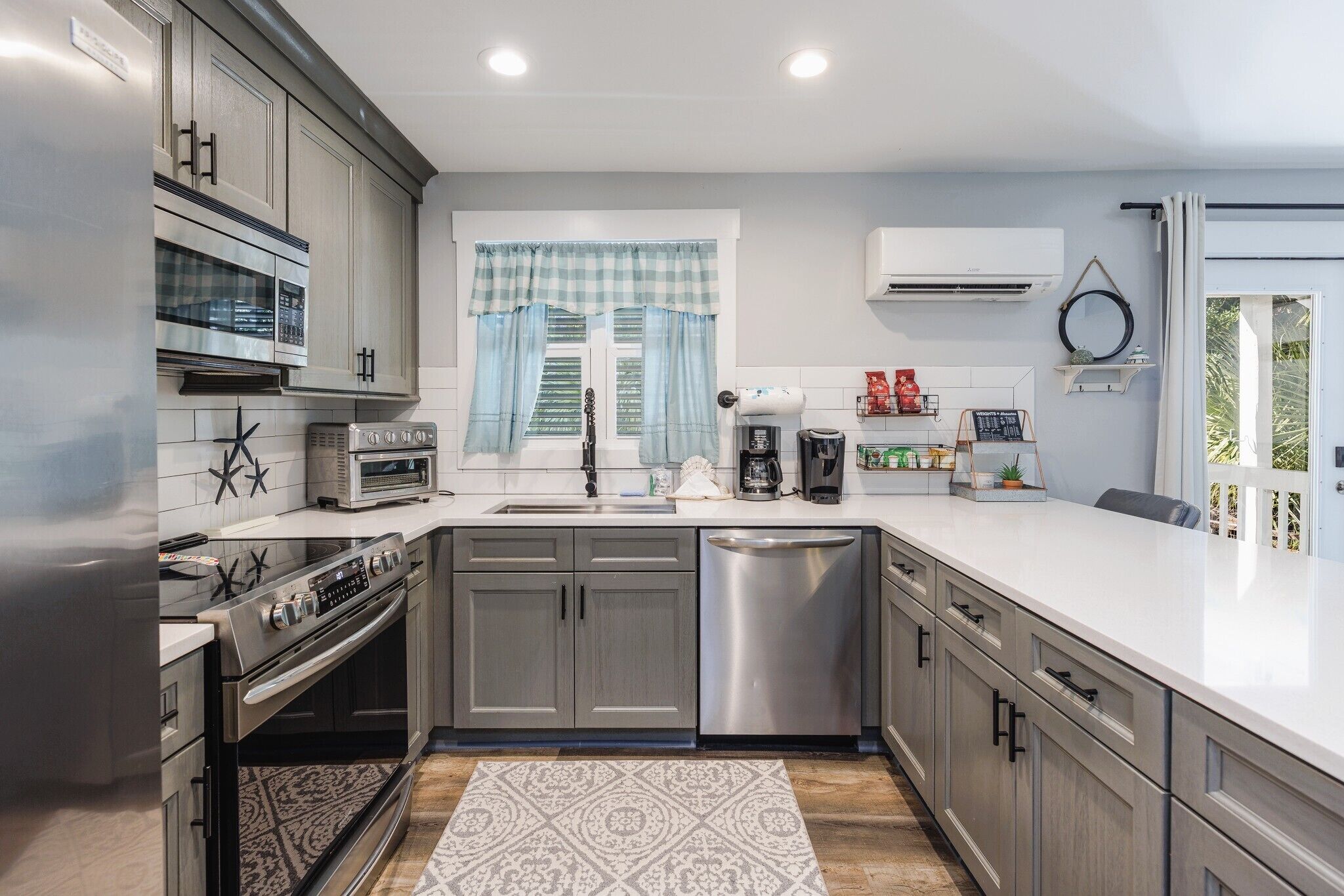 A modern kitchen with grey cabinets, a stainless steel dishwasher, a built-in oven, and a microwave.