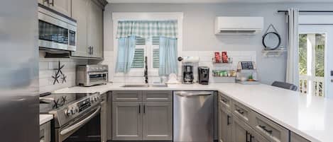 A modern kitchen with grey cabinets, a stainless steel dishwasher, a built-in oven, and a microwave.