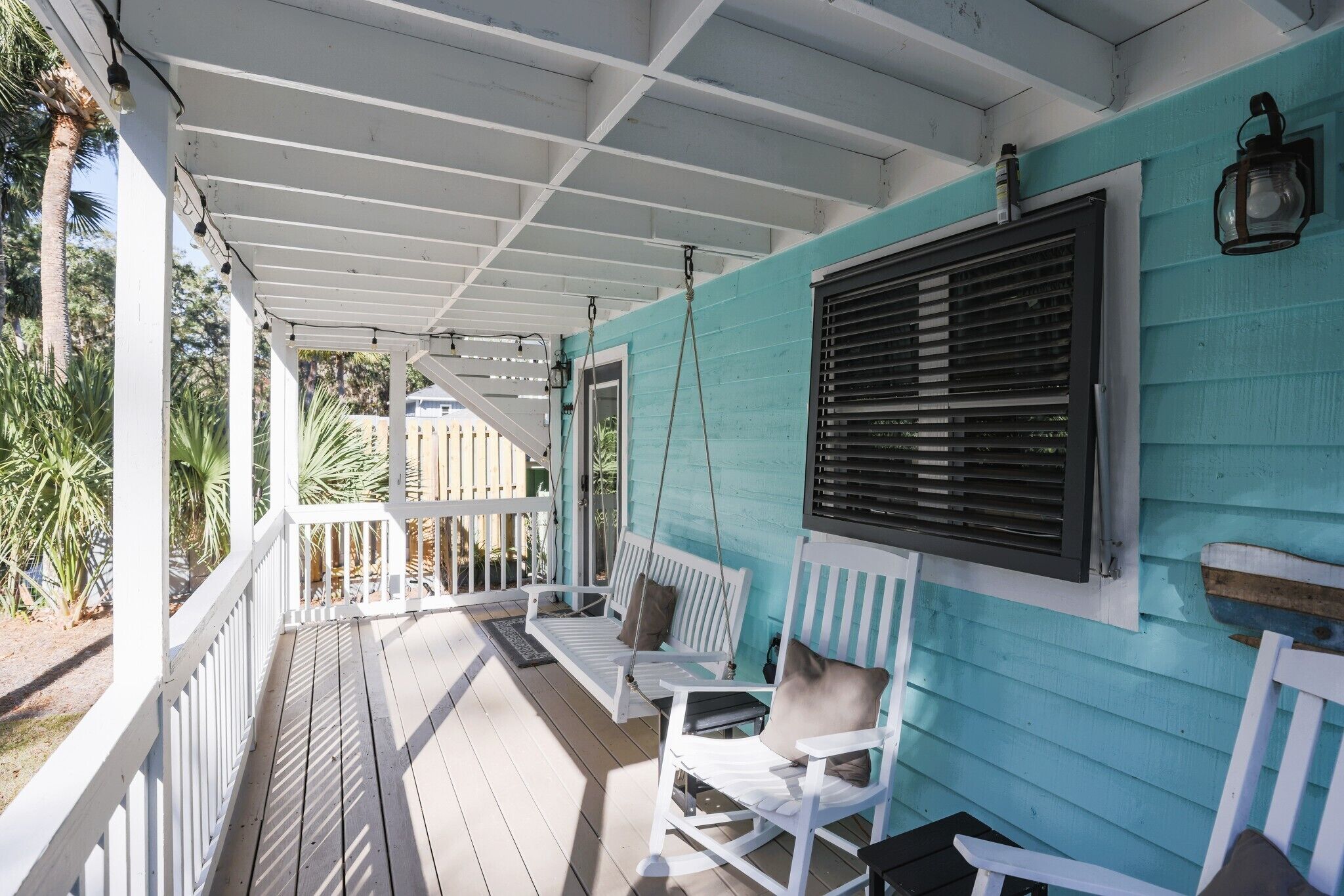 A covered porch with white railings and a swing chair.