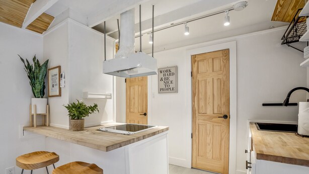 Une cuisine moderne avec des meubles blancs, un plan de travail en bois et un îlot central doté de tabourets.