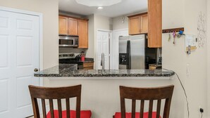Una cocina con encimeras de granito, armarios de madera, electrodomésticos de acero inoxidable y una puerta blanca.
