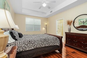 A bedroom with a bed, a dresser, a lamp, a ceiling fan, a window with blinds, and a mirror on the wall. - Beautiful Townhome close to HealthPark Medical Center (Fort Myers)