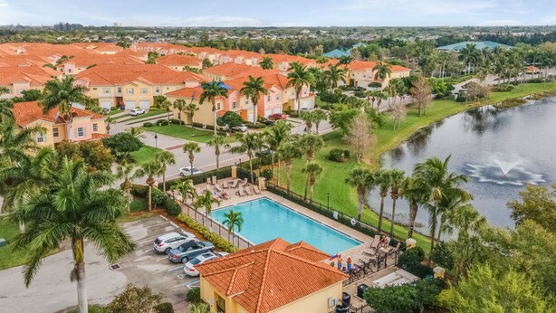 Zona residencial con piscina, palmeras y una masa de agua.