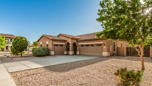 A two-story house with a tiled roof, a driveway, and a gravel front yard. - Gorgeous 3/2 Corner Lot with Firepit and Grassy Yard! (Gilbert)
