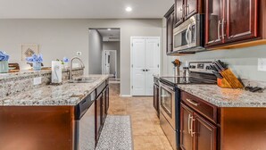 A modern kitchen with granite countertops, stainless steel appliances, and wooden cabinets. - Gorgeous 3/2 Corner Lot with Firepit and Grassy Yard! (Gilbert)
