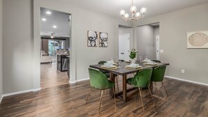 A dining area with a wooden table, green chairs, and a chandelier. - Gorgeous 3/2 Corner Lot with Firepit and Grassy Yard! (Gilbert)