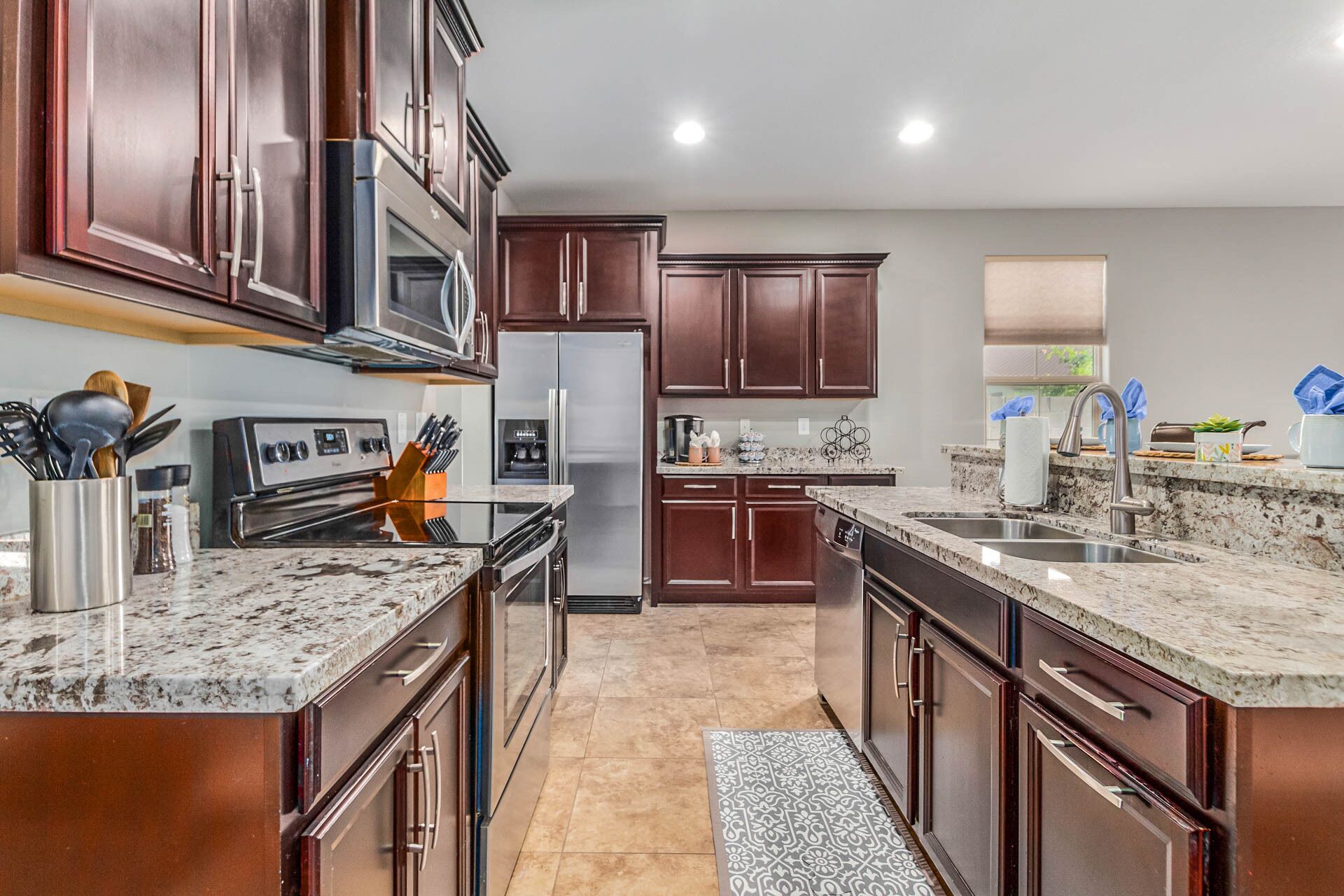 A modern kitchen with dark wood cabinets, stainless steel appliances, and granite countertops.