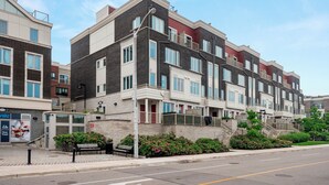 A multi-story residential building with a stone facade, large windows, and a gated entrance. - Etobicoke Suites (Toronto)