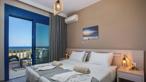 Een hotelkamer met een bed, nachtkastje, tafel met stoelen en uitzicht op zee.