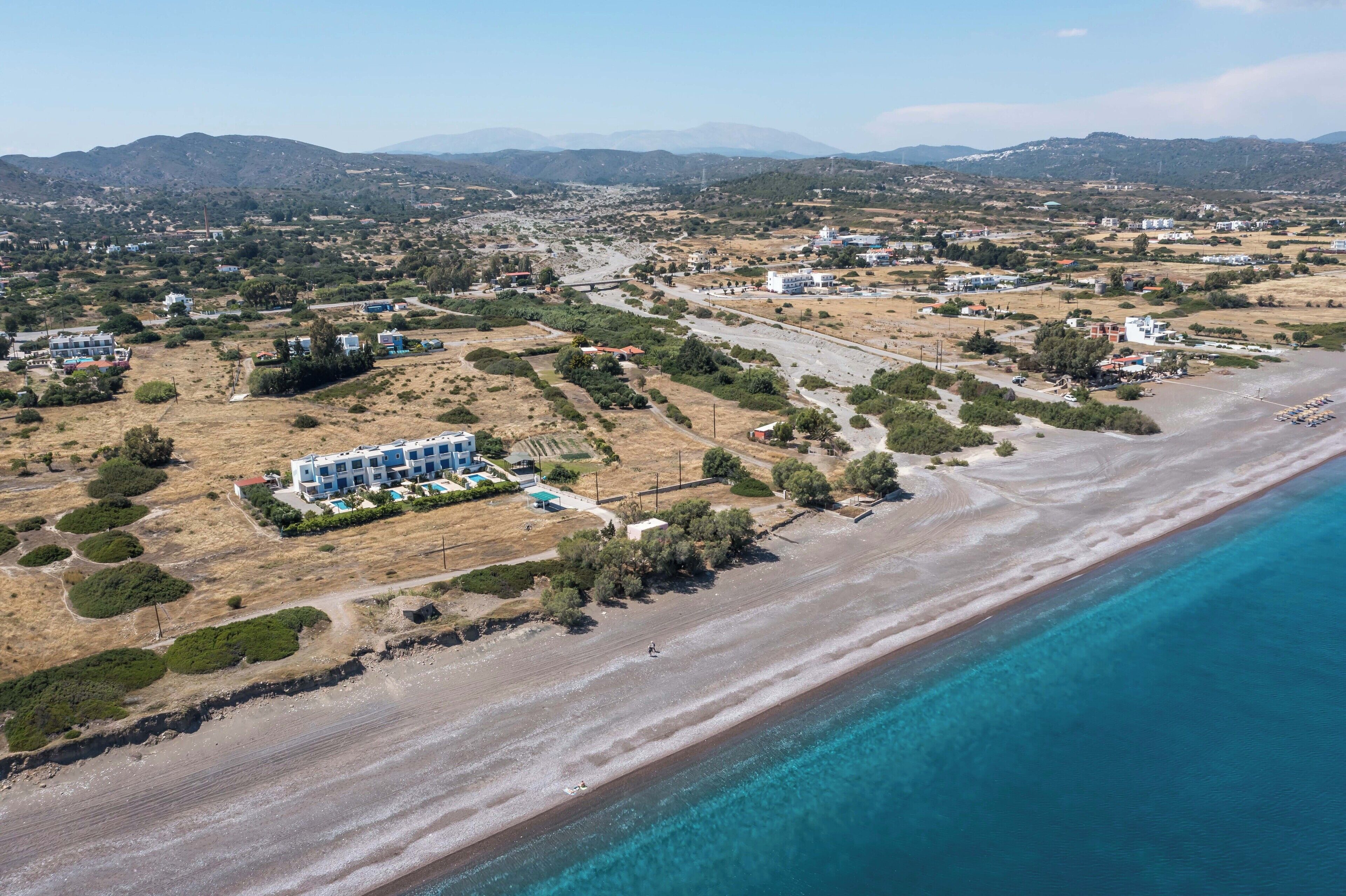 Vista aérea de una zona costera con un hotel, una playa y el paisaje circundante.