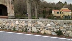 Un muro de piedra con una carretera pavimentada al frente.