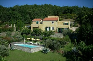 Ein zweistöckiges Haus mit Swimmingpool, umgeben von üppiger Vegetation und Bäumen.