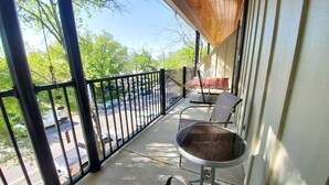 A balcony with a metal railing, a chair, a table, and a hammock.