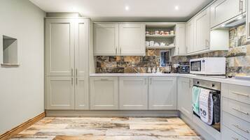 A modern kitchen with light grey cabinets, a stone backsplash, and a built-in oven.
