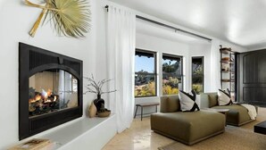 Ein modernes Wohnzimmer mit Kamin, großen Fenstern und einer gemütlichen Sitzecke.