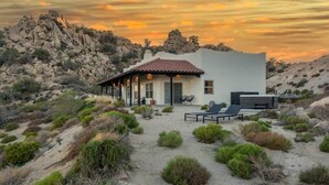 Ein modernes Haus mit Terrasse, umgeben von Wüstenpflanzen und felsigen Hügeln.