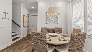 Un coin repas avec une table ronde, des chaises en osier et un luminaire suspendu.