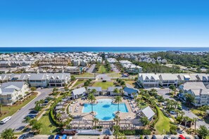 A resort with multiple buildings, a central swimming pool, and a view of the ocean.
