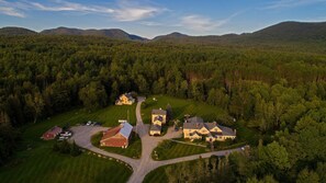 Vue aérienne d’un quartier résidentiel comprenant plusieurs maisons, une allée centrale et des collines boisées environnantes.