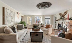 A spacious living room with a large window, a fireplace, and a ceiling light fixture.