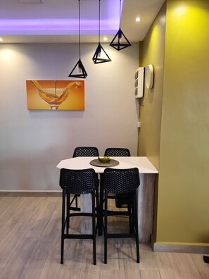 A dining area with a white table, four black chairs, a decorative bowl, and a painting on the wall.