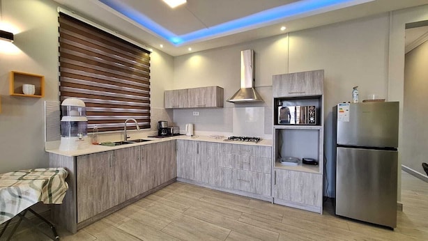Una cocina moderna con estufa integrada, refrigerador de acero inoxidable y armarios de madera.
