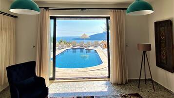 Habitación con vistas a una piscina y mobiliario exterior, un ventanal grande y suelo con baldosas estampadas.