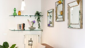 Une pièce comprenant un lit, une lampe de chevet, une étagère avec des livres et des objets décoratifs, et deux miroirs sur le mur.